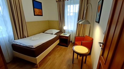a small bedroom with a bed and a chair at Apartments Gato Karlovy Vary Dalovice in Karlovy Vary