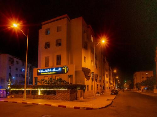 a building with a sign on the side of a street at night at Aliya Luxury Apartment - LA DUNE - AGADIR in Agadir
