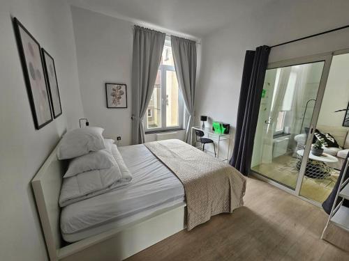 - une chambre avec un lit blanc et une grande fenêtre dans l'établissement Cosy studio center of Bruxelles, à Bruxelles