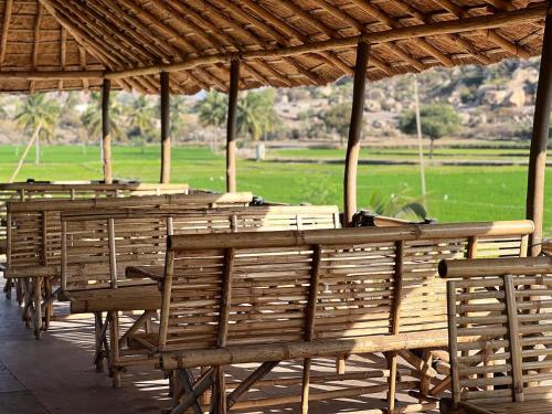 a row of wooden tables and chairs under a pavilion at Hippie Land Nature Stay in Hampi