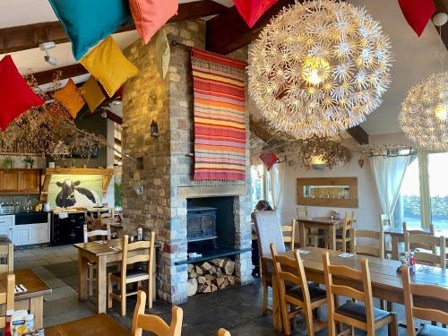 a restaurant with tables and chairs and a fireplace at Nine Yards Family Glamping @ Farrington's Farm in Bristol