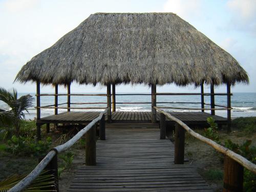 a boardwalk with benches and a thatched hut on the beach at Hotel Istirinchá in Nautla