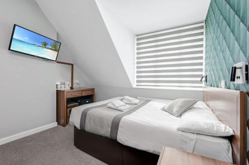 a bedroom with a bed with a tv and a window at King Solomon Hotel- Golders Green in London