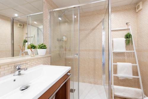 a bathroom with a sink and a glass shower at Beach & Fun: Cozy Studio in La Pineda