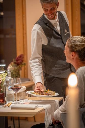 a waiter serving a plate of food at a table at Hotel Nevada in Bormio