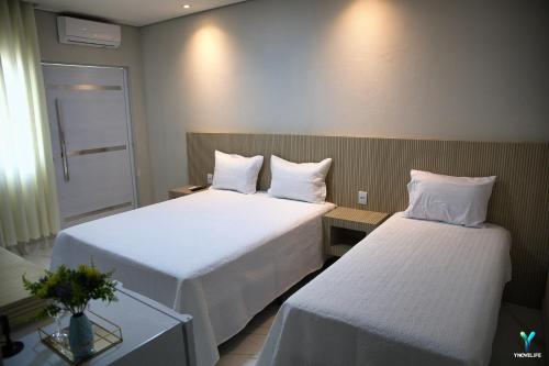 ein Hotelzimmer mit 2 Betten und einem Tisch in der Unterkunft Pousada Garden das Flores in Chapada dos Guimarães