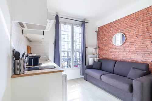 un salon avec un canapé et un mur de briques dans l'établissement Studio central Parc des Buttes-Chaumont, à Paris