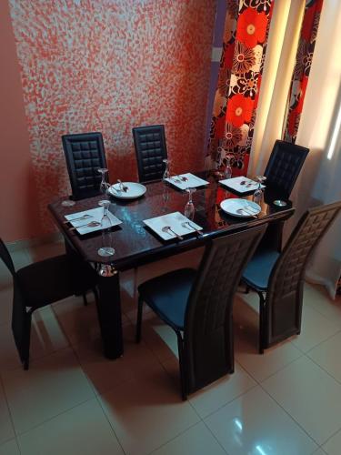 a wooden table with chairs and plates and wine glasses at Résidence privée in Bobo-Dioulasso
