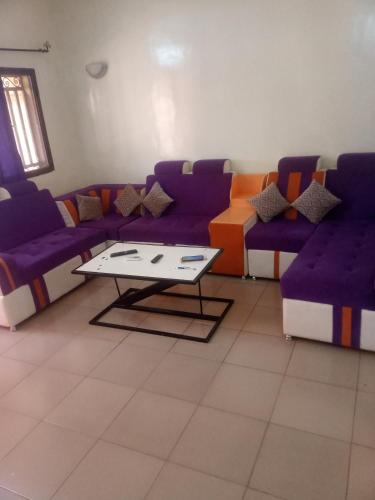 a living room with purple couches and a coffee table at Résidence privée in Bobo-Dioulasso