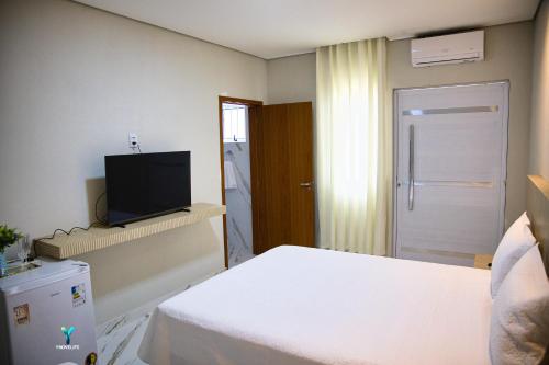 Habitación de hotel con cama y TV en Pousada Garden das Flores, en Chapada dos Guimarães