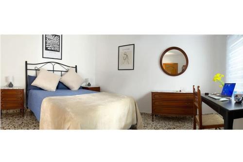 Un dormitorio con una cama y un escritorio con una computadora. en Encantadora Casa Andaluza, en Salobreña
