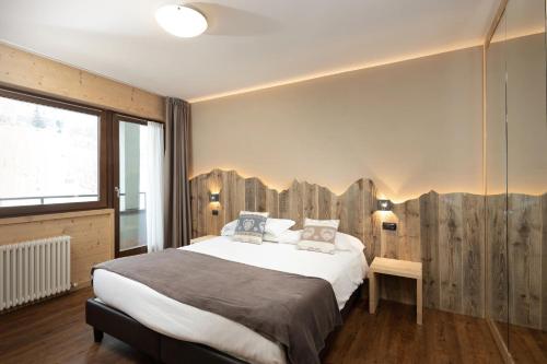 a bedroom with a large bed with a wooden wall at Hotel Nevada in Bormio