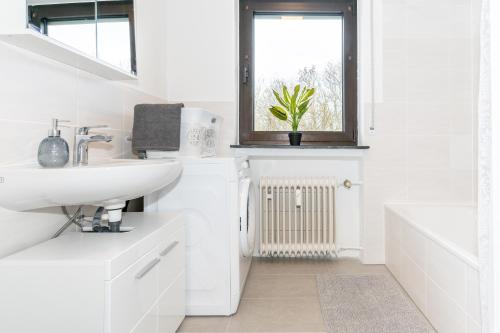 a white bathroom with a sink and a window at Moderne Ferienwohnung / Monteurswohnung mit 6 Betten in Driedorf/Herborn in Driedorf