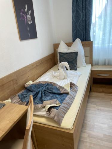 a unmade bed with a swan laying on it at Hotel Sonne in Weingarten