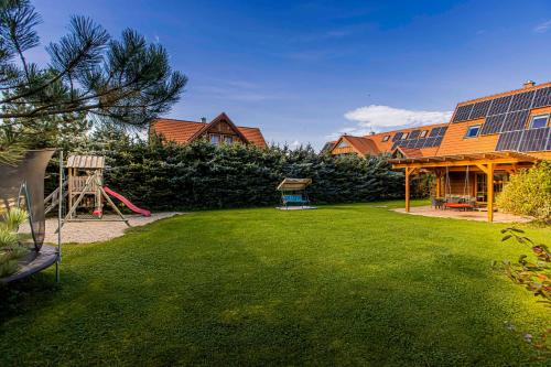 a yard with a playground and a house with solar panels at Holiday Raj in Bešeňová