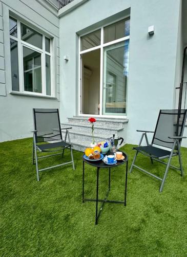 a patio with two chairs and a table on the grass at Apt Pisces - Oasi di Menaggio in Menaggio