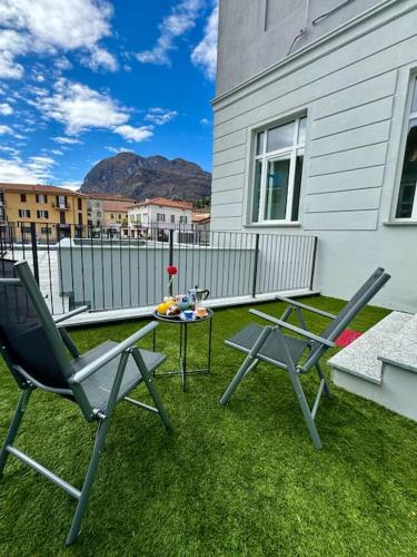 a patio with two chairs and a table on the grass at Apt Pisces - Oasi di Menaggio in Menaggio