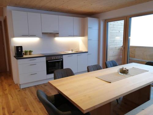 a kitchen with white cabinets and a wooden table at Ferienwohnung Berchtold in Schnepfau