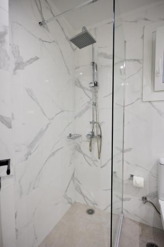 a bathroom with a shower with white marble walls at Vasilicari Apartments in Chios