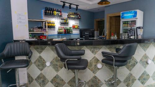 un bar con taburetes negros en una habitación en California Luxury Hotel & Suite, en Ibadán