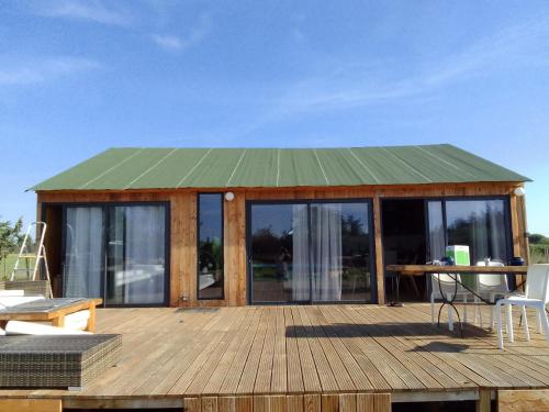 eine Hütte mit einem grünen Dach auf einem Holzdeck in der Unterkunft Chalet à la campagne in Vauvert