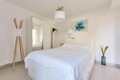 - une chambre blanche avec un lit blanc et un miroir dans l'établissement Cocon apaisant sur le Bassin d'Arcachon, à Andernos-les-Bains