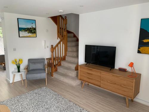 een woonkamer met een televisie en een trap bij The Apartment Boscawen Woods in Truro