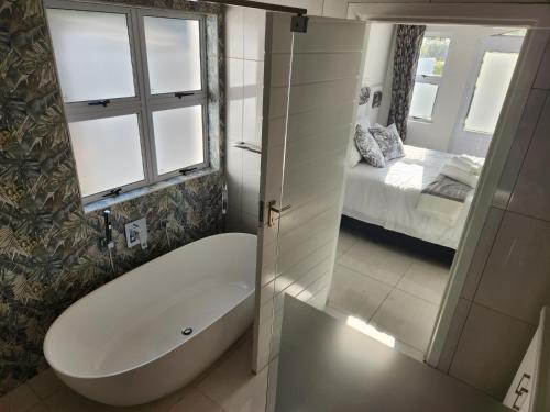 a bathroom with a tub and a bedroom with a bed at Caribbean Estates Villa R&R in Port Edward