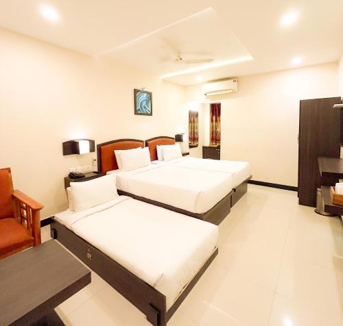 a hotel room with two beds and a chair at Shree Residency in Erode