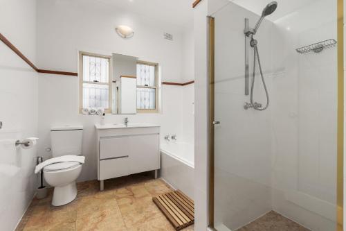 a bathroom with a toilet and a sink and a shower at Coastal Haven: Modern 3BR Apartment in Vaucluse in Sydney