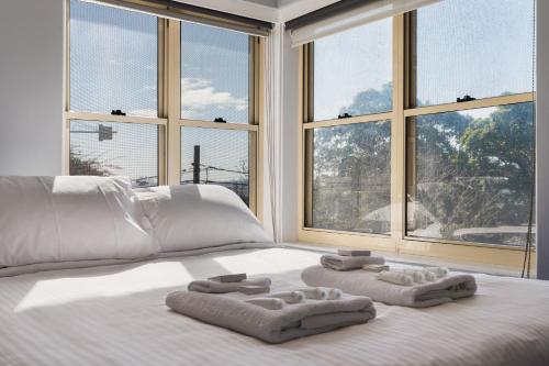 a bedroom with two towels on a bed with windows at Coastal Haven: Modern 3BR Apartment in Vaucluse in Sydney