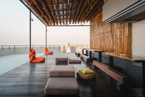 a room with benches and tables and a view of the ocean at THALAY Cha-am by THA in Cha Am
