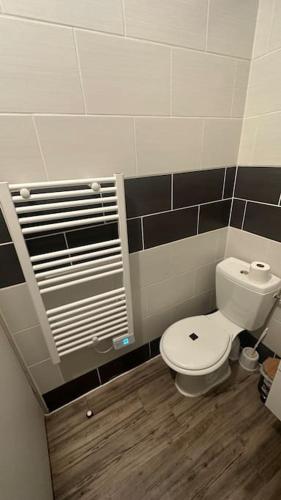 a bathroom with a white toilet and black tiles at Appartement avec terrasse in Vierzon