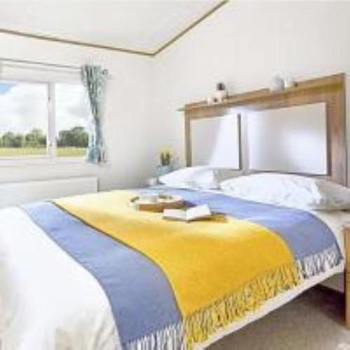 um quarto com uma cama com um cobertor amarelo e azul em WH - Smugglers Cove 04 em Aberaeron