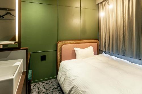 una piccola camera con letto e lavandino di Mito Sannomaru Hotel a Mito