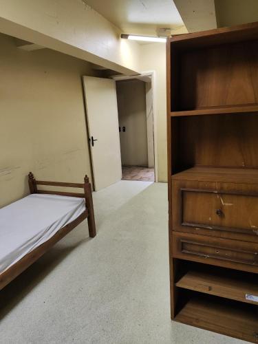 une chambre vide avec un lit et une commode dans l'établissement Quarto inferior 10 pessoas., à Caxias do Sul