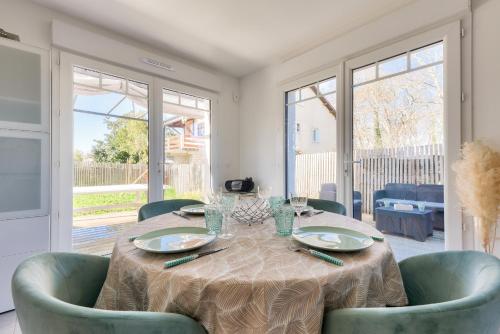 une salle à manger avec une table, des chaises et des fenêtres dans l'établissement Cocon apaisant sur le Bassin d'Arcachon, à Andernos-les-Bains