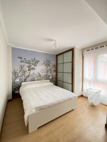 um quarto com uma grande cama branca com um quadro na parede em Apartamento muy cerca de la playa em Ribeira