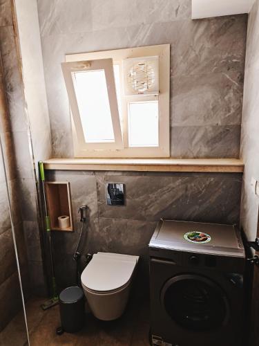 a small bathroom with a toilet and a window at Royal Elegance Room in Sheikh Zayed