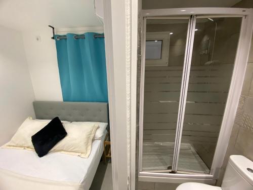 baño pequeño con ducha y cama en Suites con baño privado frente a la estación de metro L5 Fira Barcelona, en Hospitalet de Llobregat