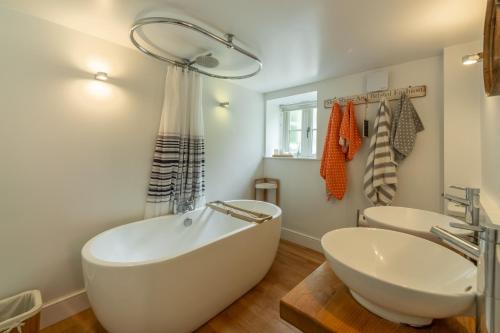 a white bathroom with a tub and a sink at The Maltings in Trunch