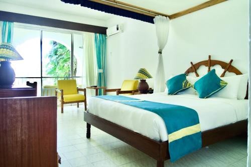 a bedroom with a large bed and a desk and chairs at Plaza Beach Hotel in Bamburi