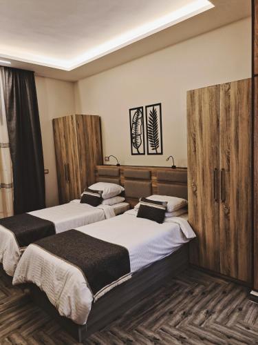 two beds in a room with wooden dividers at Royal Elegance Room in Sheikh Zayed