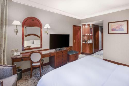 a hotel room with a bed and a desk with a television at Madinah Hilton Hotel in Al Madinah