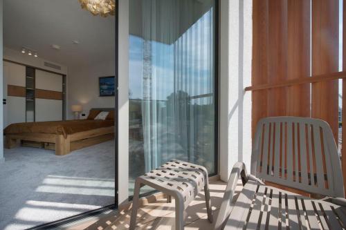 een kamer met een balkon met een bed en een stoel bij Apartament Premium PINEA 203 in Pobierowo