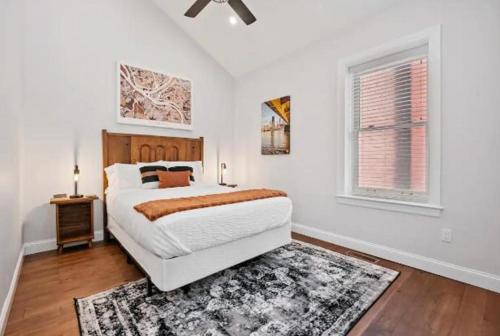 a white bedroom with a bed and a window at Adorable Reymer Carriage Repair Loft! in Pittsburgh