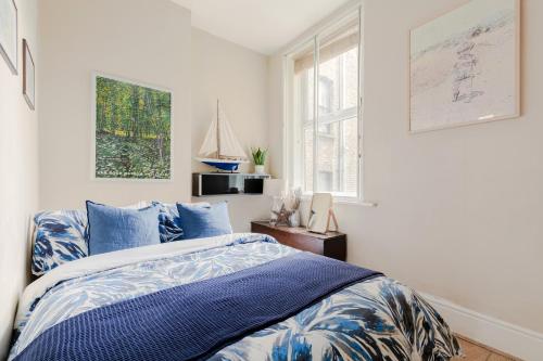 - une chambre avec un lit bleu et blanc et une fenêtre dans l'établissement Stylish Flat with Artistic Flair in Central London, à Londres