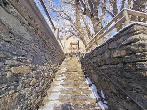 a stone wall with stairs in front of a building at Grand Hotel Ceresole Reale studio apartment in Ceresole Reale