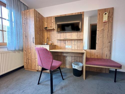 a room with a desk and a chair and a tv at Hotel Ochsen in Ammerbuch
