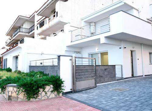 a white building with a gate in front of it at Thetis Apartments in Furci Siculo